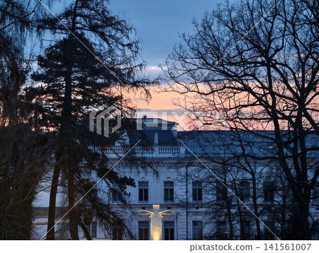 Charming mansion at dusk transition. Graceful neoclassical house illuminated by gentle sunset light Charming mansion at dusk transition. Graceful neoclassical house illuminated by gentle sunset light 141561007