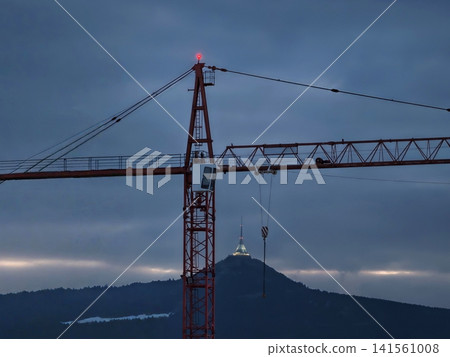 Silhouette in twilight. Serene industrial landscape featuring crane silhouette above misty hills at dusk 141561008
