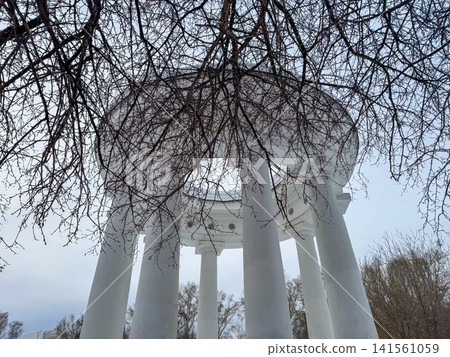 White classical gazebo with tall columns and circular roof surrounded by bare trees in a winter landscape White classical gazebo with tall columns and circular roof surrounded by bare trees in a winter landscape 141561059