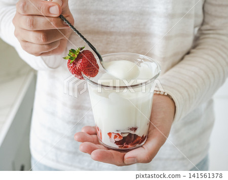 Hands stirring strawberry yogurt with a spoon Hands stirring strawberry yogurt with a spoon 141561378