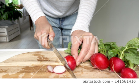 Hands slicing fresh red radishes Hands slicing fresh red radishes 141561416