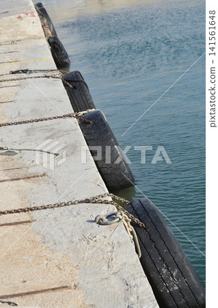 Old tires used as boat fenders on a concrete pier Old tires used as boat fenders on a concrete pier 141561648