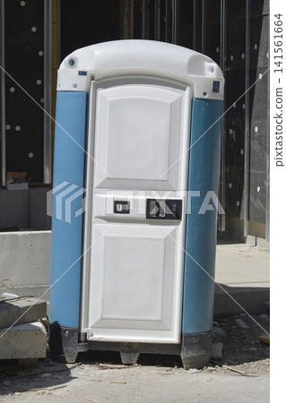 Portable blue and white plastic chemical toilet at a construction site 141561664