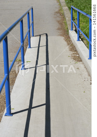 Accessible concrete ramp with blue metal handrails Accessible concrete ramp with blue metal handrails 141561668