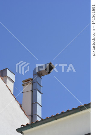 Industrial exhaust pipe attached to a chimney on a roof Industrial exhaust pipe attached to a chimney on a roof 141561691