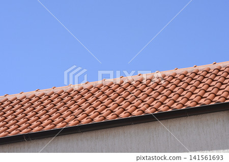 Orange tiled roof with gutter against a clear blue sky Orange tiled roof with gutter against a clear blue sky 141561693