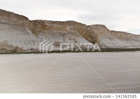 White chalk cliffs along a sandy beach under a cloudy sky White chalk cliffs along a sandy beach under a cloudy sky 141562585