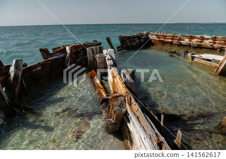 Abandoned wooden shipwreck partially submerged in clear blue water Abandoned wooden shipwreck partially submerged in clear blue water 141562617