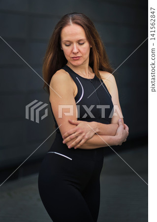 A confident woman in sportswear poses with folded arms and a steady expression outdoors. The photo connects exercise habits, self esteem, stress relief, and psychological strength. A confident woman in sportswear poses with folded arms and a steady expression outdoors. The photo connects exercise habits, self esteem, stress relief, and psychological strength. 141562847