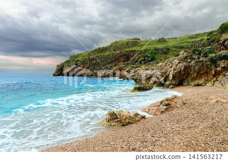 Dramatic coastal cliffs meet a turbulent sea under an overcast sky Dramatic coastal cliffs meet a turbulent sea under an overcast sky 141563217