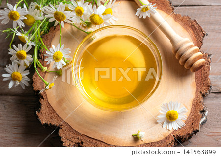 Golden honey in bowl with chamomile flowers, fresh honey Golden honey in bowl with chamomile flowers, fresh honey 141563899