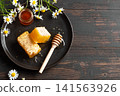 Golden honeycomb on white plate with chamomile flowers, fresh honey 141563926