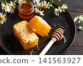 Golden honeycomb on black plate with chamomile flowers, fresh honey 141563927