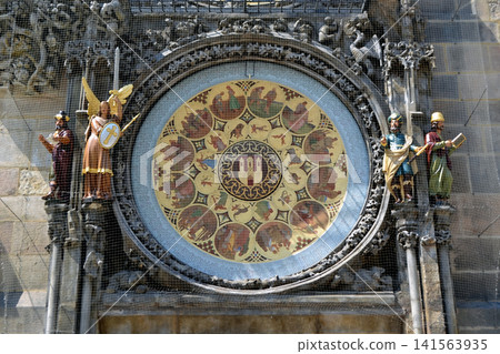 Decorative zodiac calendar disk of the Prague astronomical clock with carved statues on the historic tower facade for heritage background Decorative zodiac calendar disk of the Prague astronomical clock with carved statues on the historic tower facade for heritage background 141563935
