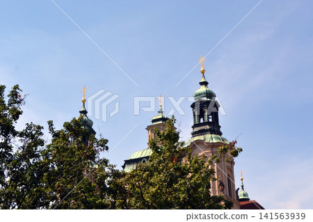 Green copper domes and church towers peeking above trees against blue sky for travel background and architecture banner Green copper domes and church towers peeking above trees against blue sky for travel background and architecture banner 141563939