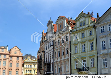 Row of pastel historic townhouses with ornate facades and red tile roofs for city background and travel poster design. Old Town Square of Prague Row of pastel historic townhouses with ornate facades and red tile roofs for city background and travel poster design. Old Town Square of Prague 141563940