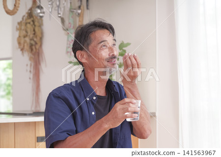 A senior man attempting to take oral medication. A senior man attempting to take oral medication. 141563967