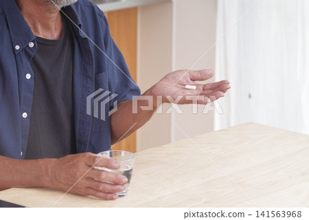 A senior man attempting to take oral medication. A senior man attempting to take oral medication. 141563968