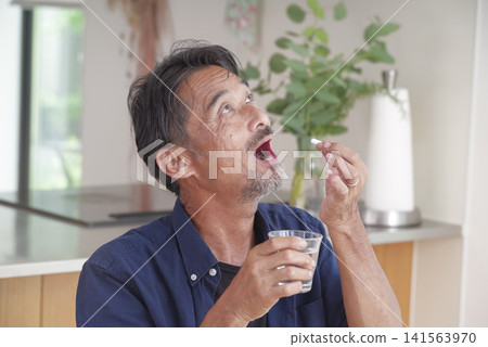 一位老年男子試圖服用口服藥物。 一位老年男子試圖服用口服藥物。 141563970