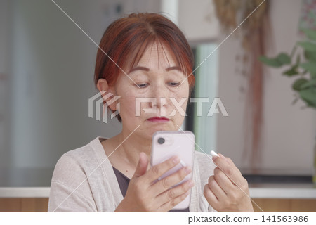 一位女性透過智慧型手機和藥物來管理自己的健康。 141563986