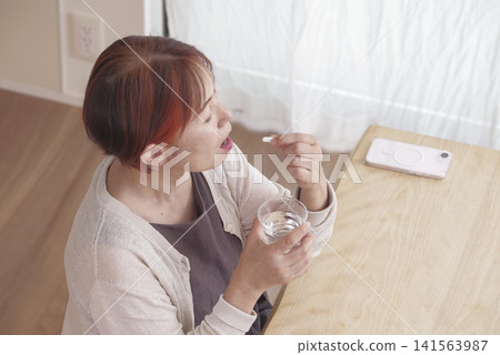 一位老年婦女正在嘗試服用口服藥物。 一位老年婦女正在嘗試服用口服藥物。 141563987