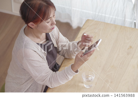 A woman manages her health using her smartphone and pills. A woman manages her health using her smartphone and pills. 141563988