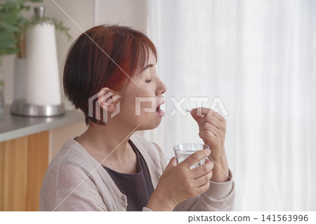 A senior woman trying to take oral medication. A senior woman trying to take oral medication. 141563996