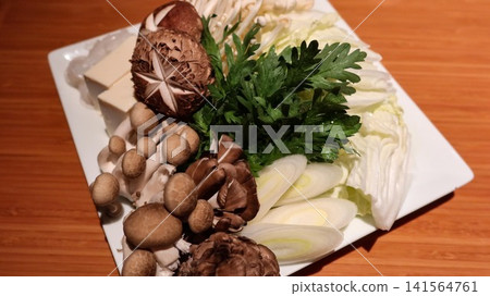 close up of fresh Japanese hot pot shabushabu ingredients beautifully arranged on a white plate, including Shiitake, shimeji mushrooms, crisp chrysanthemum greens, sliced leeks, napa cabbage and tofu. close up of fresh Japanese hot pot shabushabu ingredients beautifully arranged on a white plate, including Shiitake, shimeji mushrooms, crisp chrysanthemum greens, sliced leeks, napa cabbage and tofu. 141564761