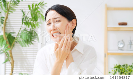 A middle-aged woman is experiencing a toothache in her back teeth. (Keywords: cavities, wisdom teeth, dental care, dentist, pain, stress, trouble, worries, treatment, dental clinic) A middle-aged woman is experiencing a toothache in her back teeth. (Keywords: cavities, wisdom teeth, dental care, dentist, pain, stress, trouble, worries, treatment, dental clinic) 141564817