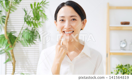 一位中年婦女展現她潔白的牙齒。牙齒美白、牙齒護理、牙醫、蛀牙治療、植牙、口腔護理 一位中年婦女展現她潔白的牙齒。牙齒美白、牙齒護理、牙醫、蛀牙治療、植牙、口腔護理 141564819