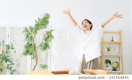 一位中年婦女在房間裡跳舞。她放鬆、微笑、快樂、喜悅、有趣、精力充沛、跳舞、滿足、自由、無拘無束,是一位家庭主婦。 一位中年婦女在房間裡跳舞。她放鬆、微笑、快樂、喜悅、有趣、精力充沛、跳舞、滿足、自由、無拘無束,是一位家庭主婦。 141564841
