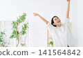 A middle-aged woman cheering in her room. Happy, joyful, having fun, energetic, positive, relaxed, smiling, satisfied. 141564842