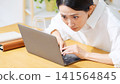 A middle-aged woman glued to her laptop. Serious, work, investment, gambling, engrossed, focused, work, attention, anxiety 141564845