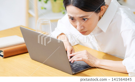 A middle-aged woman glued to her laptop. Serious, work, investment, gambling, engrossed, focused, work, attention, anxiety A middle-aged woman glued to her laptop. Serious, work, investment, gambling, engrossed, focused, work, attention, anxiety 141564845
