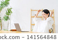 A middle-aged woman makes a triumphant gesture while looking at her laptop. (Keywords: passing an exam, cheering, taking on a challenge, winning, watching sports, victory, live streaming, supporting a fan) 141564848