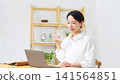 A middle-aged woman drinking water. Relaxation, hydration, unwinding, office, taking medication, pharmaceuticals, health, healthcare, medical. 141564851