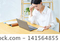 A middle-aged woman ponders while looking at her laptop. Household finances, accounting, administrative tasks, anxiety, worries, dissatisfaction, questions, management, calculator, DX. 141564855