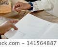 A close-up capture of a traditional wedding ceremony moment, highlighting the groom seated beside the officiant  141564887
