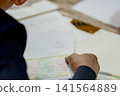 A close-up capture of a traditional wedding ceremony moment, highlighting the groom seated beside the officiant  141564889
