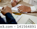 A close-up capture of a traditional wedding ceremony moment, highlighting the groom seated beside the officiant  141564891