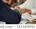 A close-up capture of a traditional wedding ceremony moment, highlighting the groom seated beside the officiant  141564892