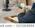 A close-up capture of a traditional wedding ceremony moment, highlighting the groom seated beside the officiant  141564894