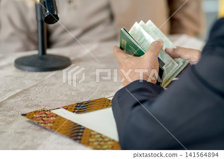 A close-up capture of a traditional wedding ceremony moment, highlighting the groom seated beside the officiant A close-up capture of a traditional wedding ceremony moment, highlighting the groom seated beside the officiant 141564894