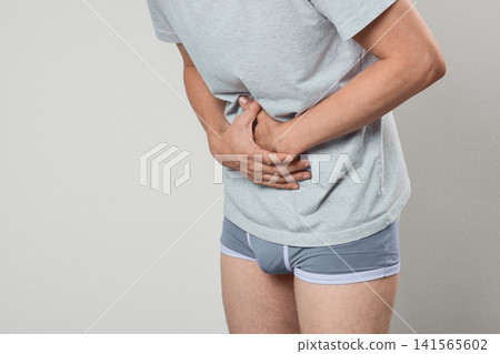 Man holding his painful stomach due to acute gastritis and peptic ulcer. Gastroenterology diagnostic consultation and abdominal pain treatment. Man holding his painful stomach due to acute gastritis and peptic ulcer. Gastroenterology diagnostic consultation and abdominal pain treatment. 141565602