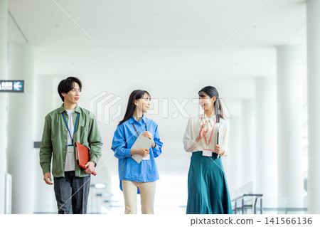 Male and female business team walking down an office corridor Male and female business team walking down an office corridor 141566136
