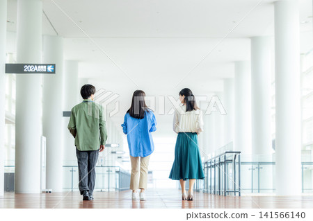 一支由男性和女性組成的商務團隊正沿著辦公室走廊行走。 一支由男性和女性組成的商務團隊正沿著辦公室走廊行走。 141566140
