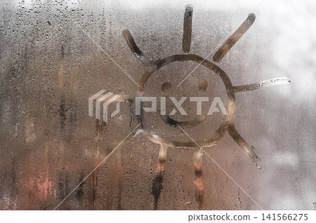 Sun drawing on wet glass window with condensation drops. Sun drawing on wet glass window with condensation drops. 141566275