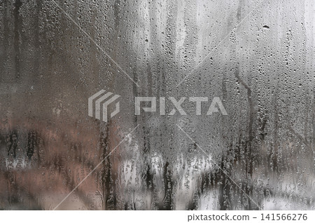 Heavy condensation covers cold glass window pane inside house. Heavy condensation covers cold glass window pane inside house. 141566276