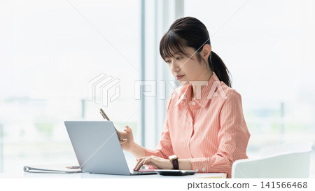 一位女性/女商人正在使用電腦和智慧型手機 一位女性/女商人正在使用電腦和智慧型手機 141566468