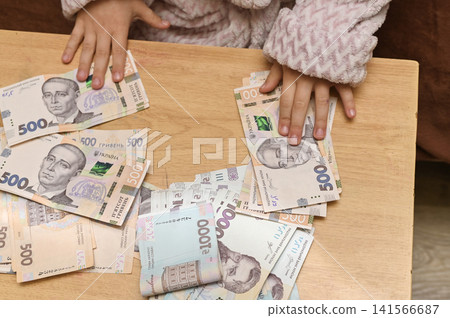 Child hands covering money bills. Child hands covering money bills. 141566687